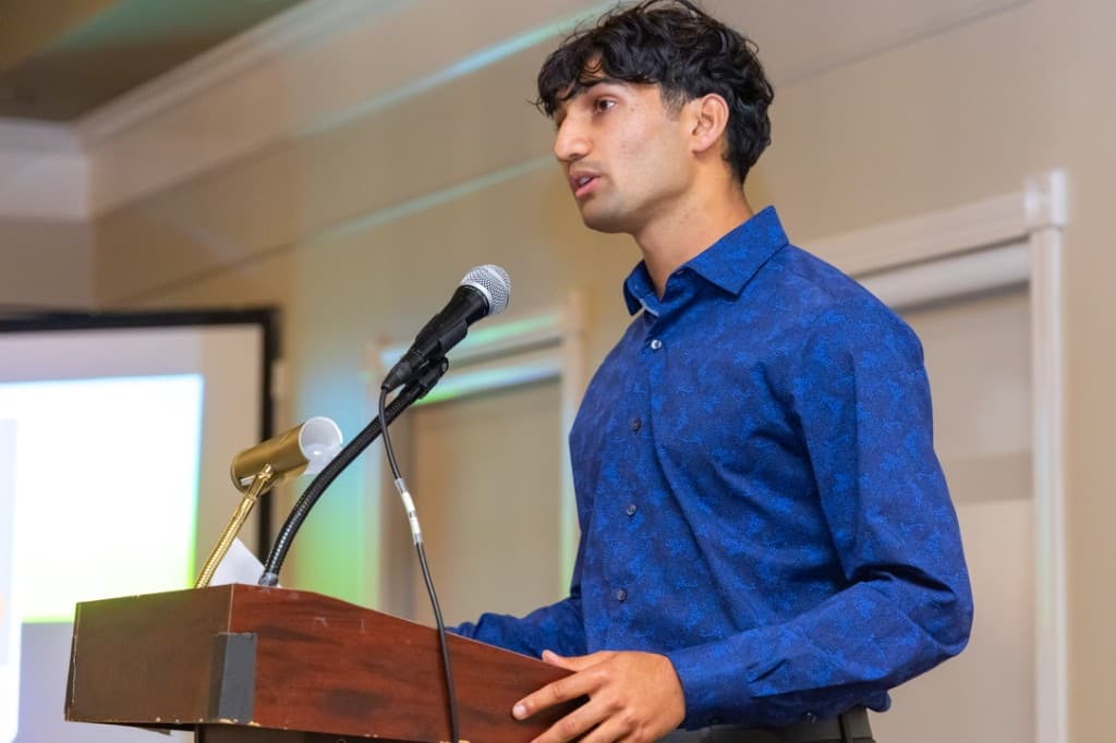Amar speaking at a conference podium