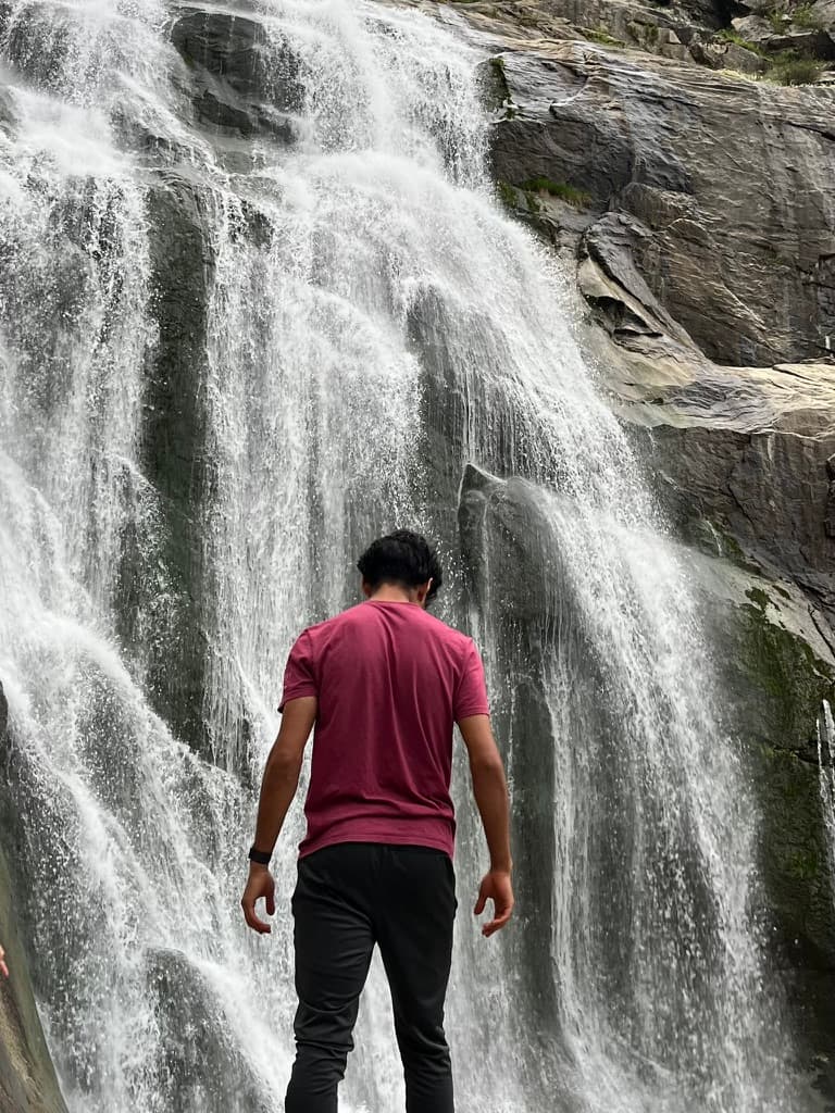 Amar standing before a waterfall