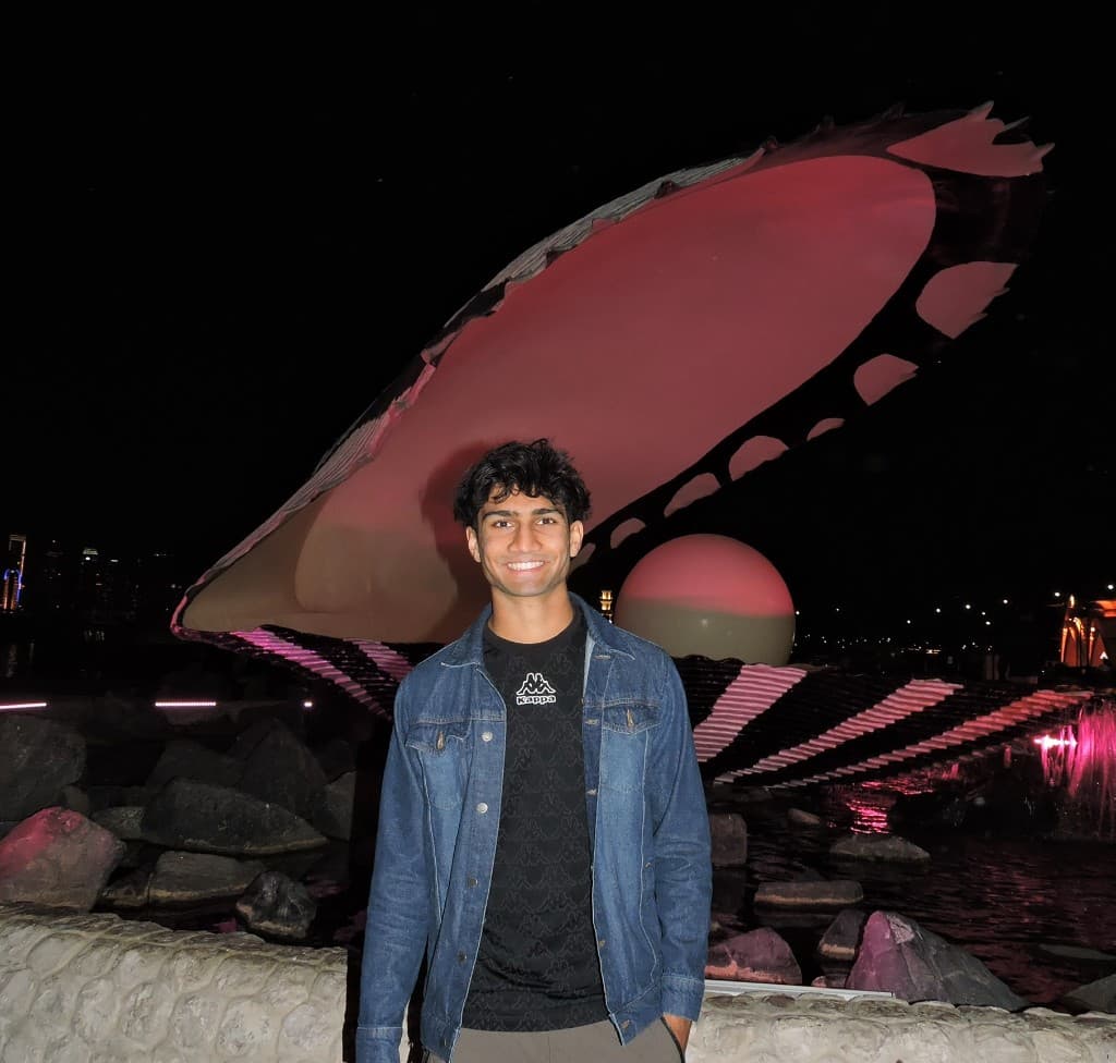 Amar at night in front of a glowing oyster shell sculpture